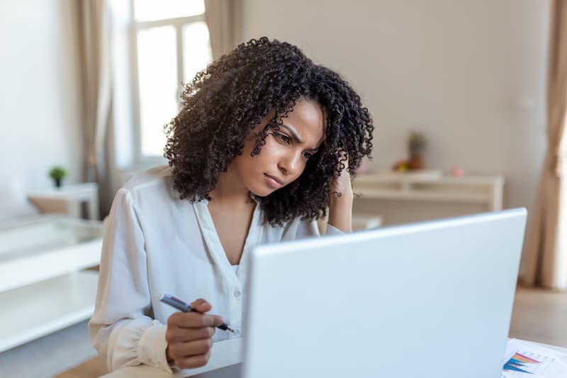 A business woman on  a computer confused by SharePoint issues while working on SOPs. 